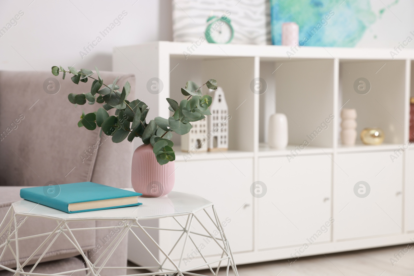 Photo of Stylish coffee table with book and eucalyptus at home