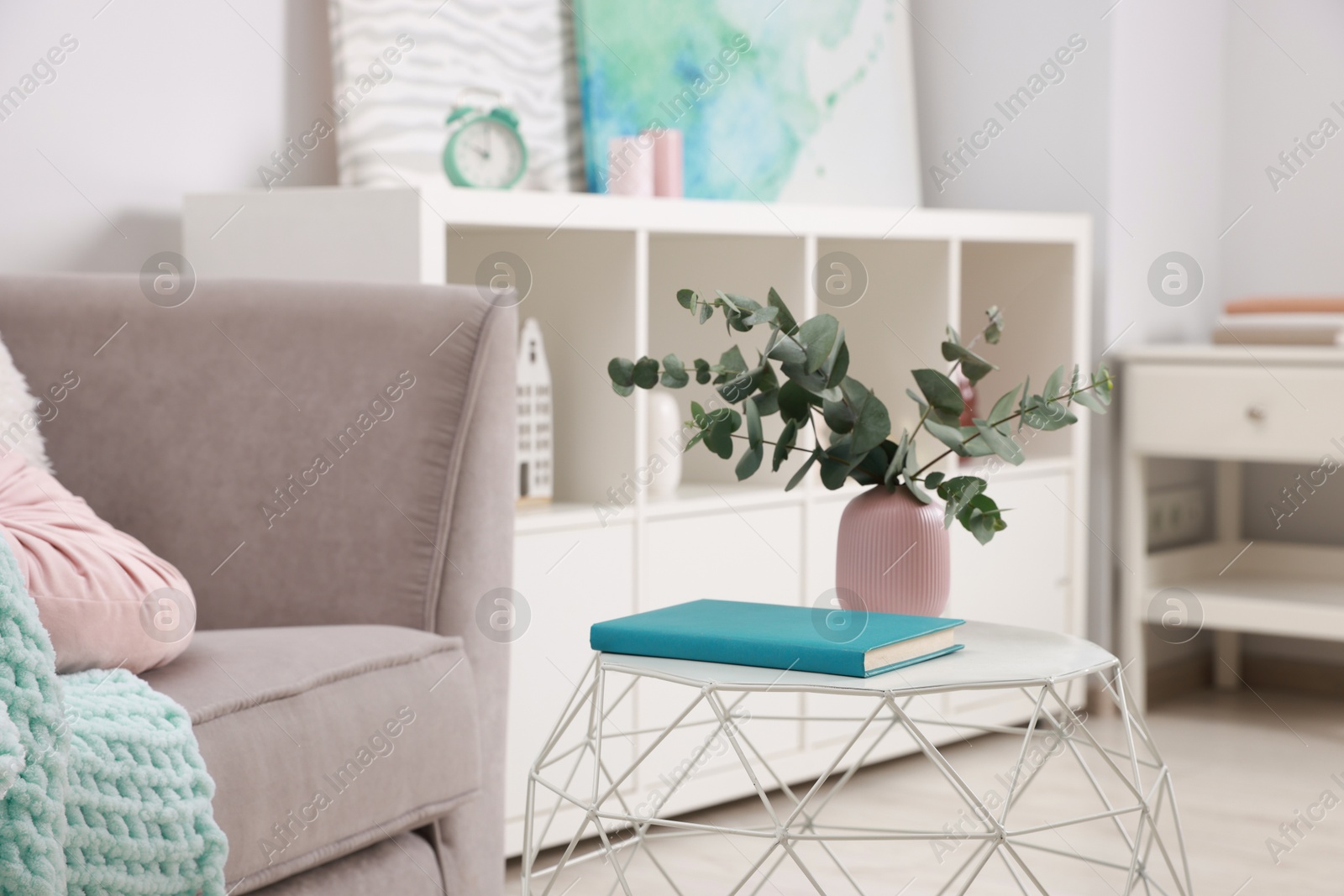 Photo of Stylish coffee table with book and eucalyptus at home