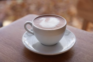 Photo of Cup of aromatic coffee on wooden table in cafe, closeup