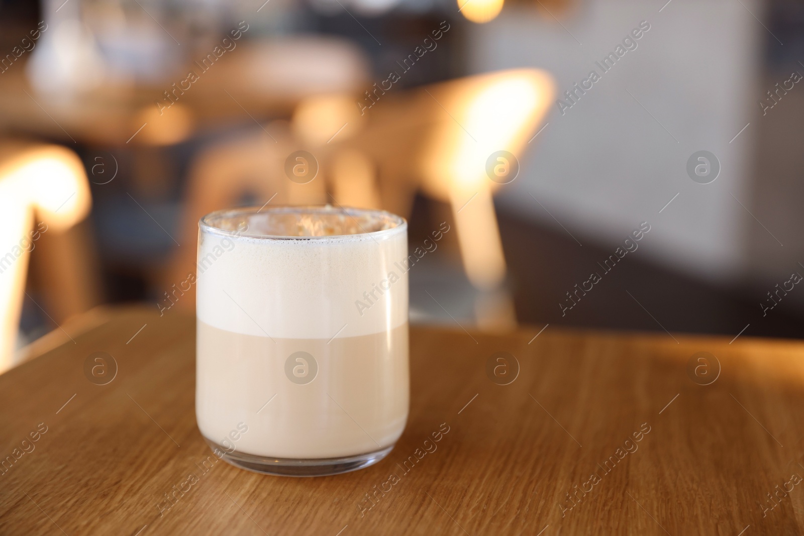 Photo of Glass of aromatic coffee on wooden table in cafe, closeup. Space for text