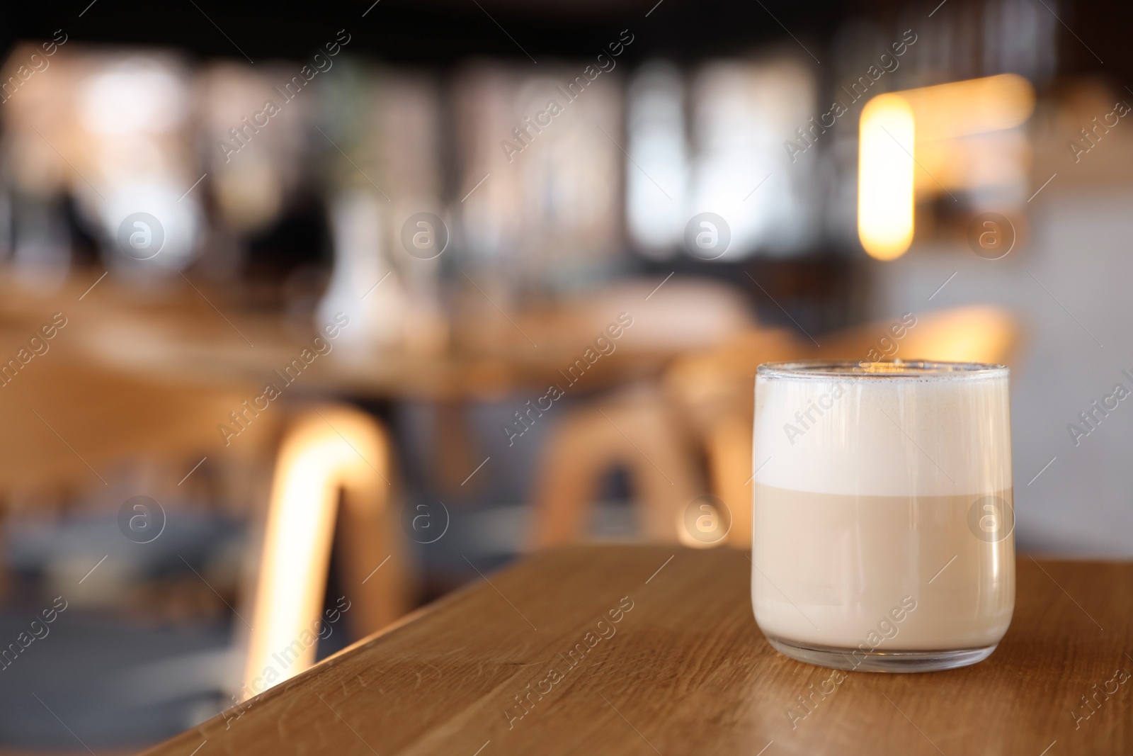 Photo of Glass of aromatic coffee on wooden table in cafe, closeup. Space for text