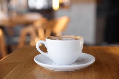 Photo of Cup of aromatic coffee on wooden table in cafe, closeup