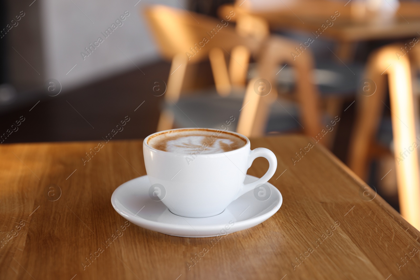 Photo of Cup of aromatic coffee on wooden table in cafe, closeup