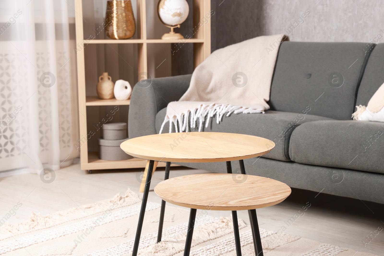 Photo of Stylish nesting tables near sofa at home