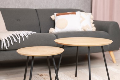 Photo of Stylish nesting tables near sofa at home