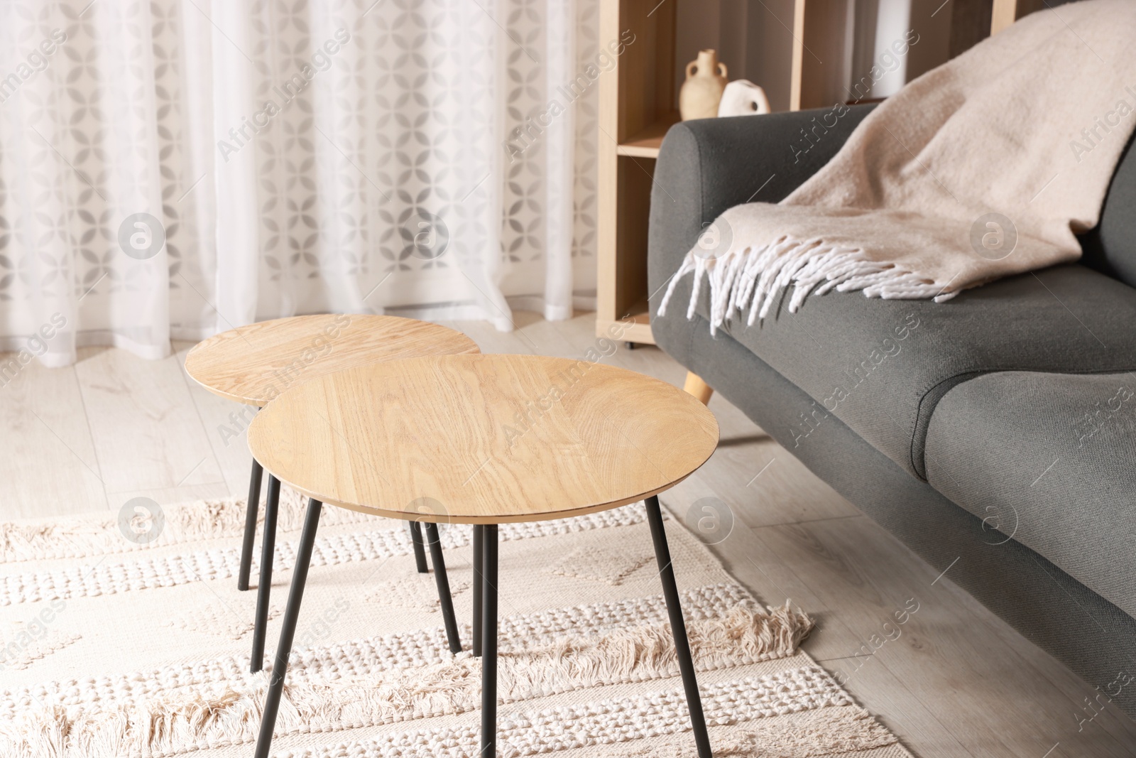 Photo of Stylish nesting tables near sofa at home