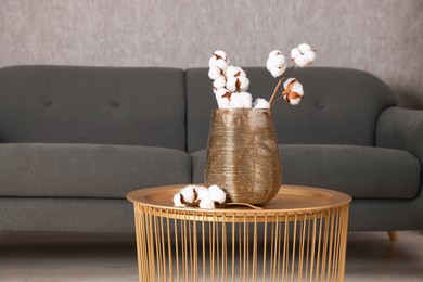 Photo of Coffee table with cotton flowers near sofa at home