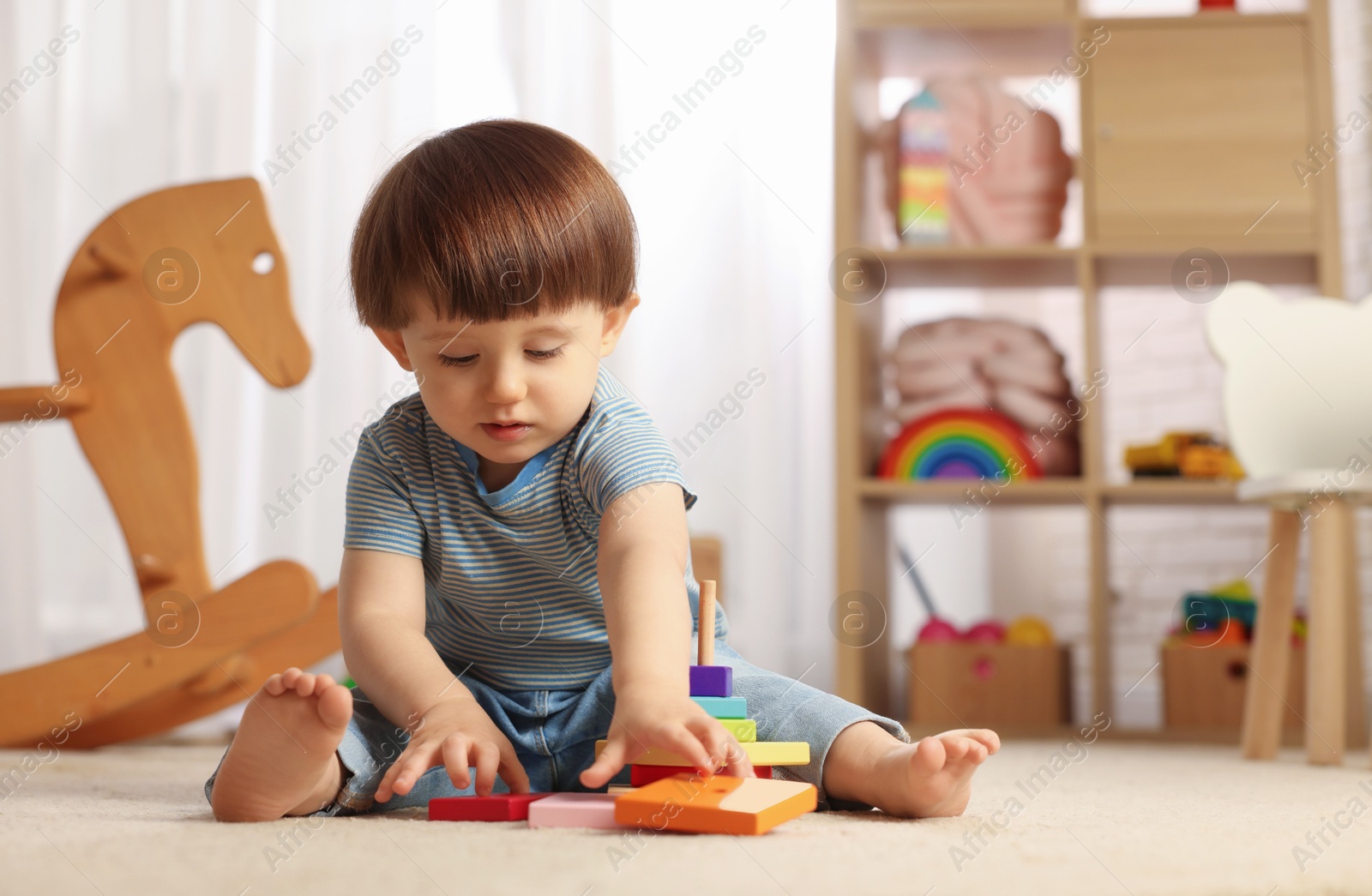 Photo of Cute little boy playing with toy pyramid on floor at home, space for text