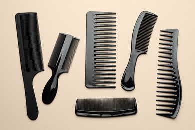 Photo of Different black plastic combs on beige background, top view