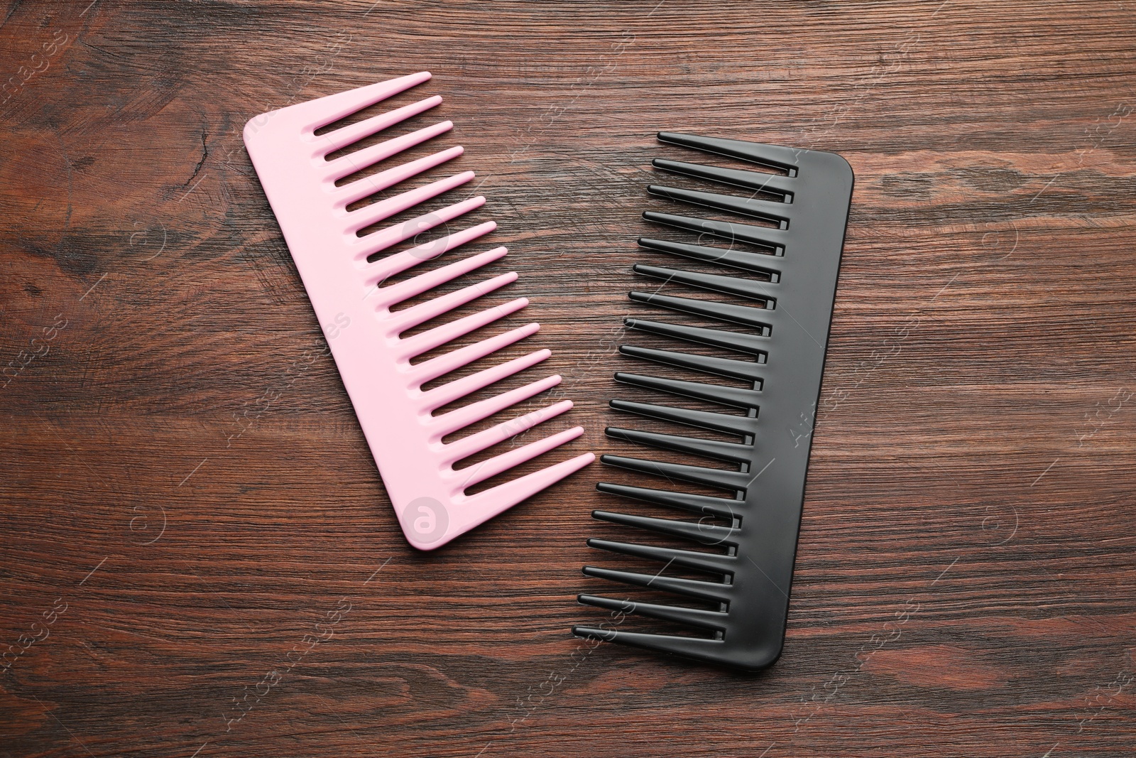 Photo of Different plastic hair combs on wooden background, top view