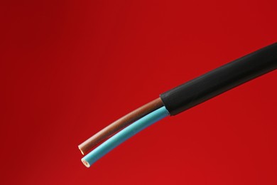 Photo of Stripped electrical wire on red background, closeup