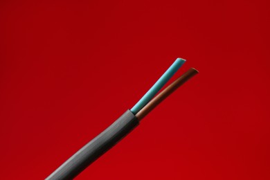 Photo of Stripped electrical wire on red background, closeup