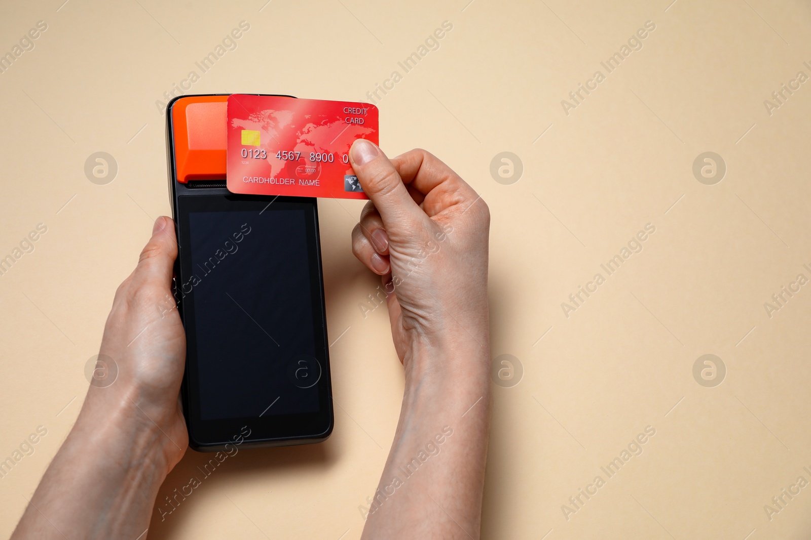 Photo of Woman with credit card using payment terminal on beige background, closeup. Space for text