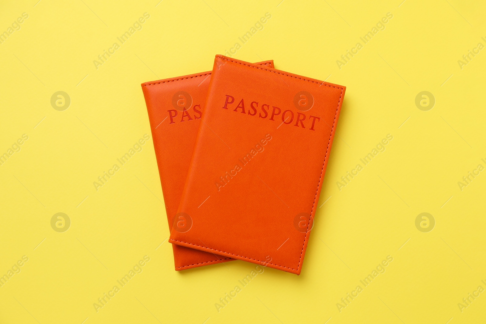 Photo of Passports in bright covers on yellow background, top view