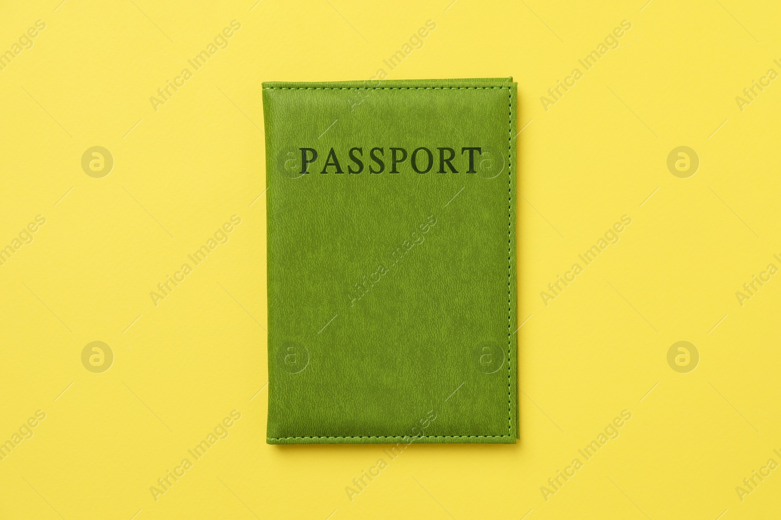 Photo of Passport in bright cover on yellow background, top view