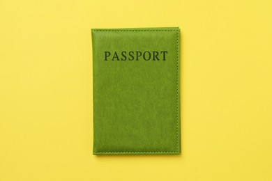 Photo of Passport in bright cover on yellow background, top view