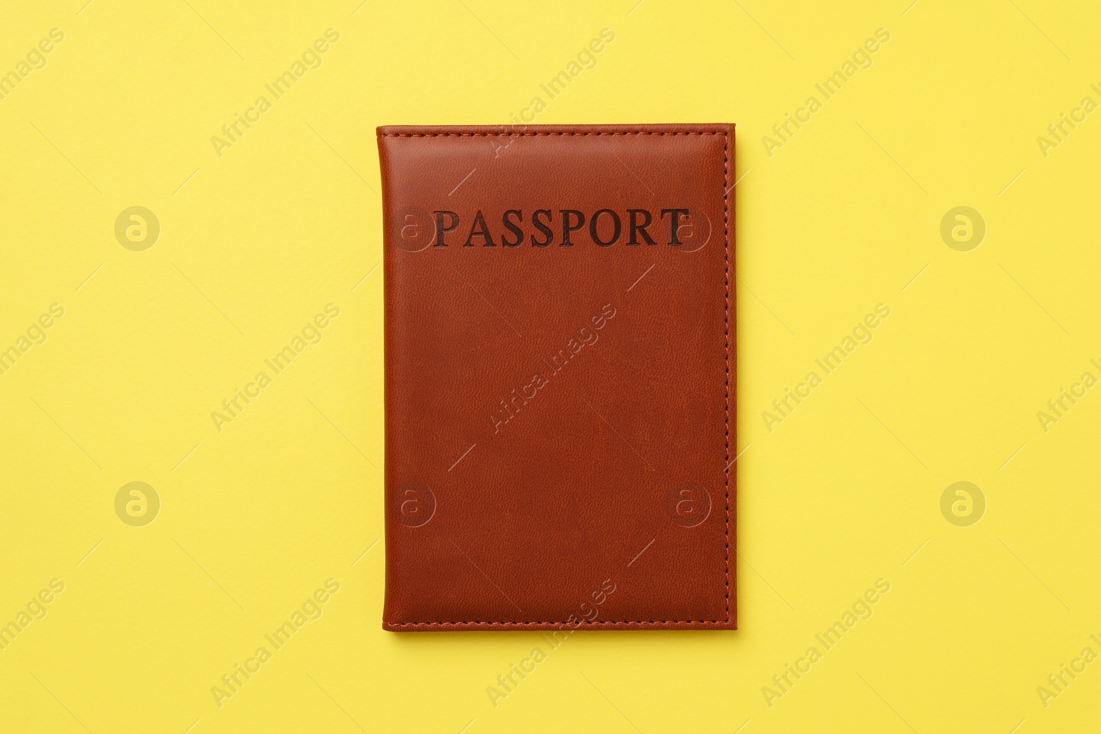 Photo of Passport in leather cover on yellow background, top view