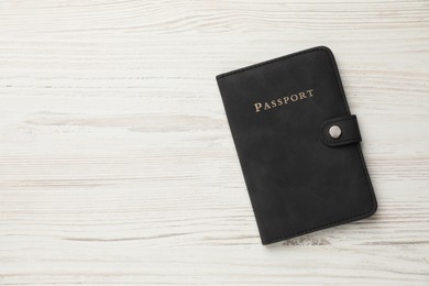 Photo of Passport in black cover on light wooden table, top view. Space for text