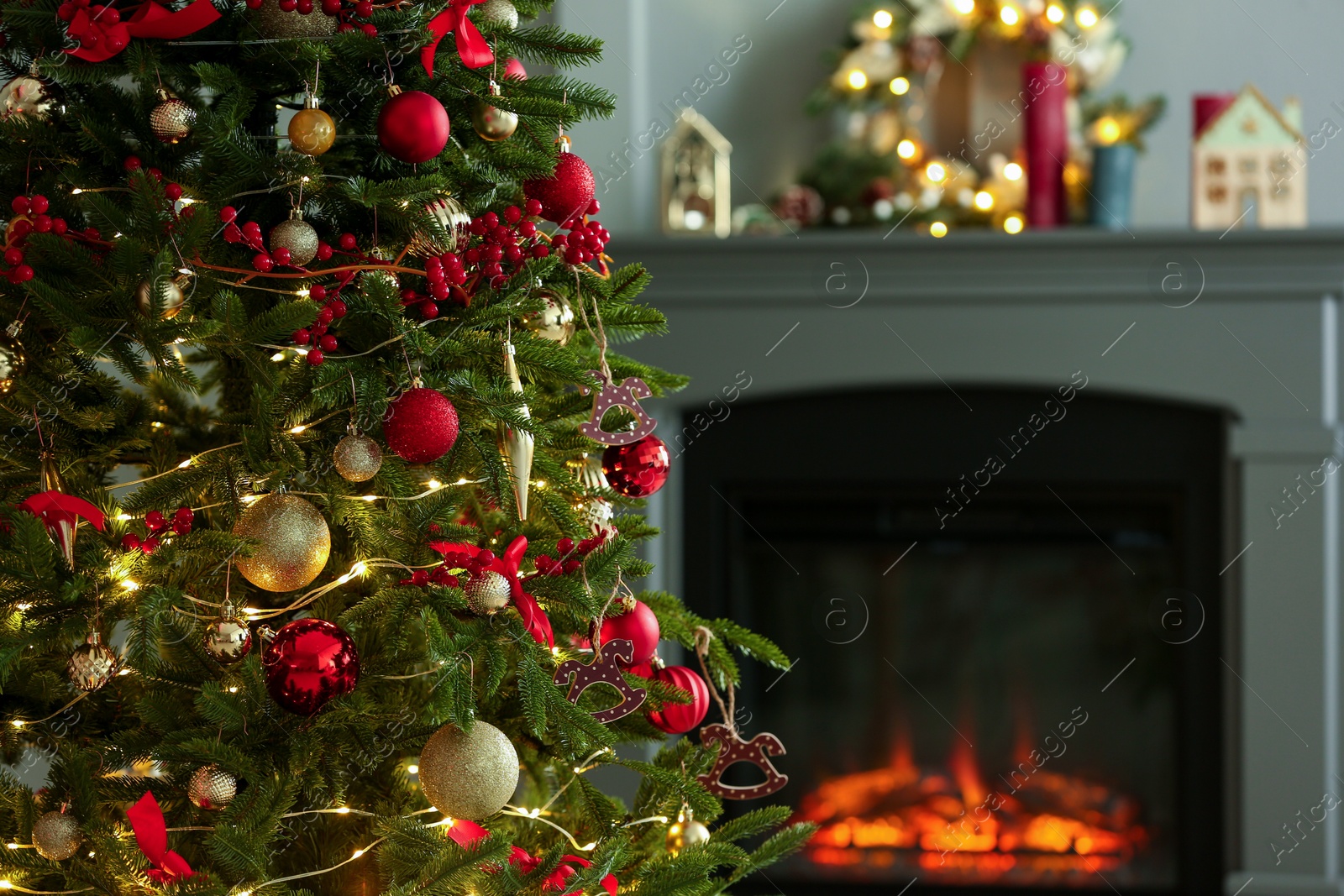 Photo of Beautiful decorated Christmas tree near fireplace at home, closeup. Space for text