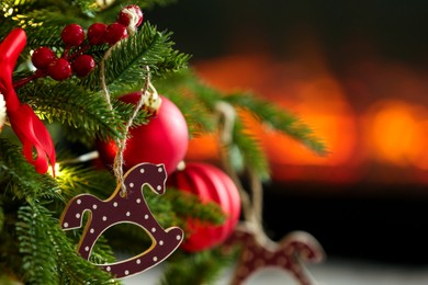 Photo of Beautiful Christmas tree decorated with horse toy, other ornaments and festive lights indoors, closeup. Space for text