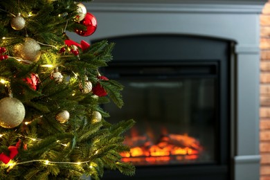 Photo of Beautiful decorated Christmas tree near fireplace at home, closeup. Space for text