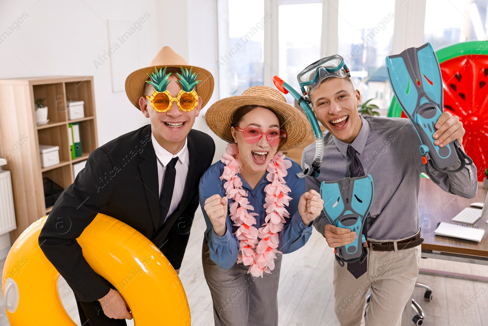 Photo of Colleagues with different beach accessories having fun in office