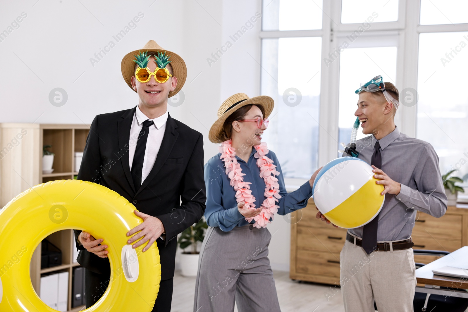 Photo of Colleagues with different beach accessories having fun in office