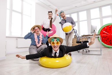 Photo of Happy coworkers with different beach accessories having fun in office, low angle view