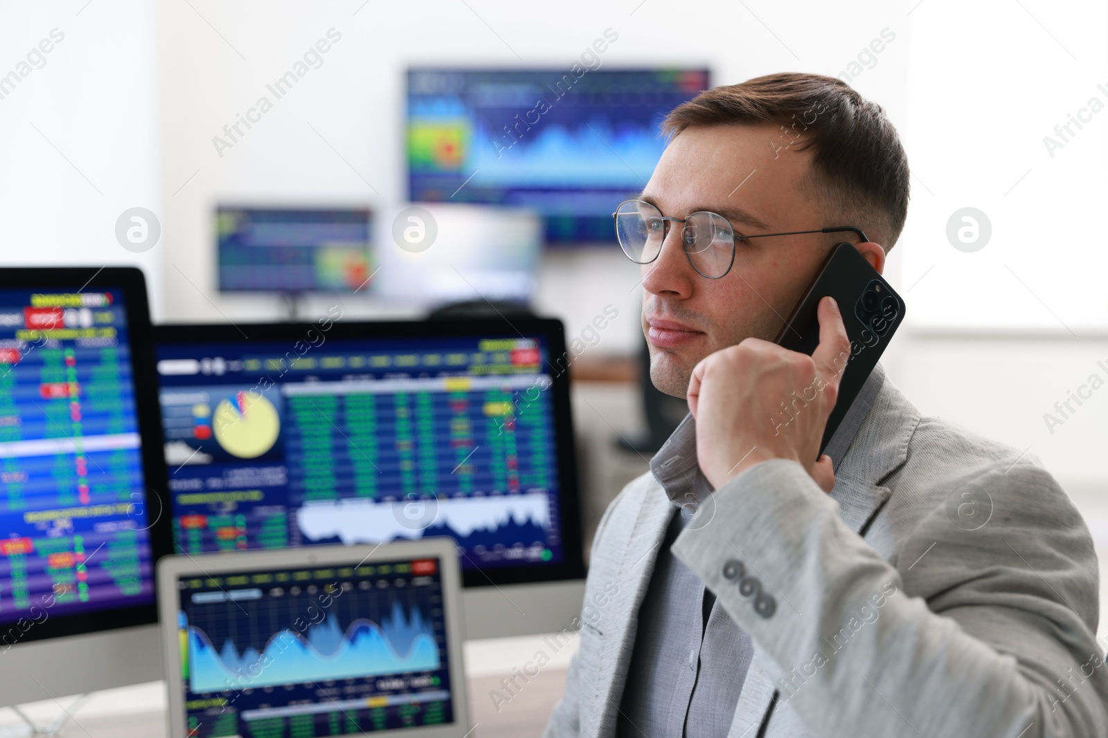 Photo of Financial trading specialist talking on phone in office