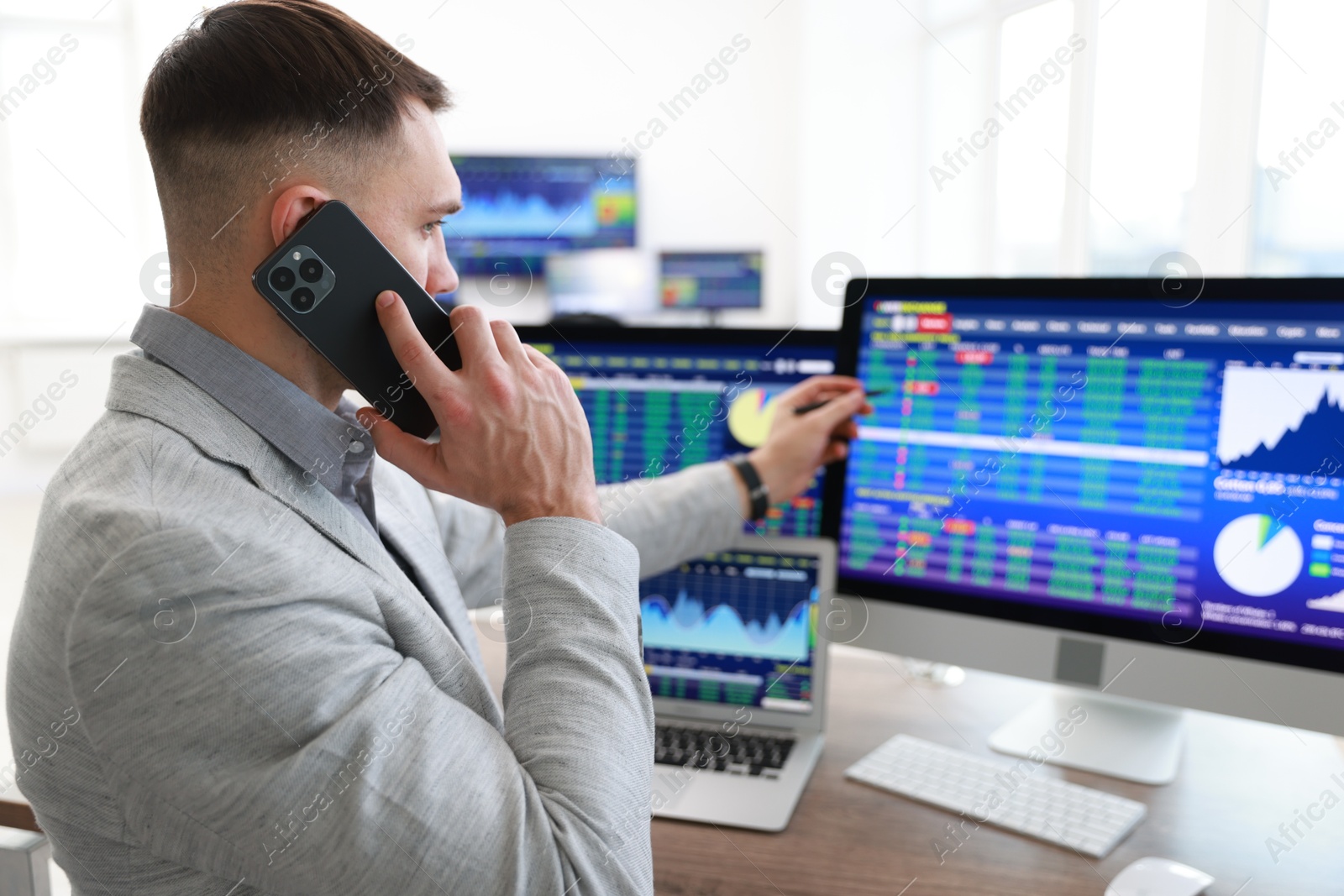 Photo of Financial trading specialist talking on phone in office