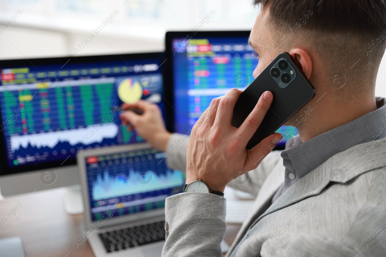 Photo of Financial trading specialist talking on phone in office