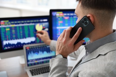 Photo of Financial trading specialist talking on phone in office