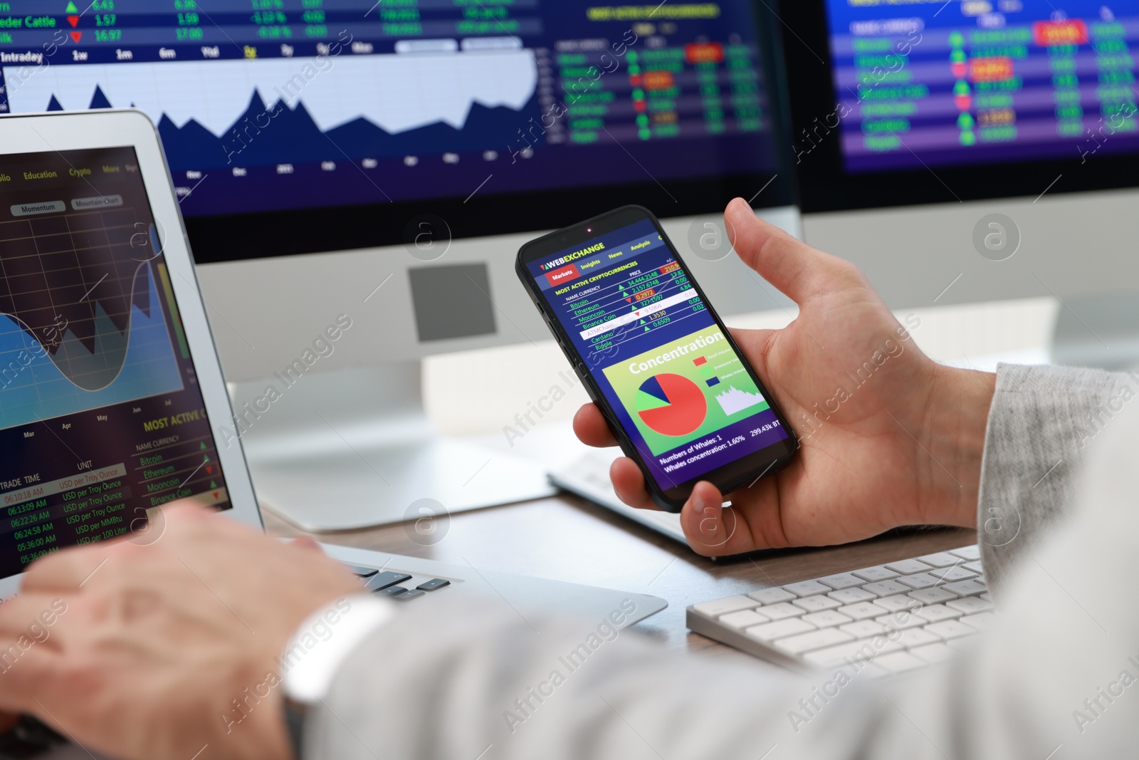 Photo of Financial trading specialist with smartphone and laptop at table in office, closeup