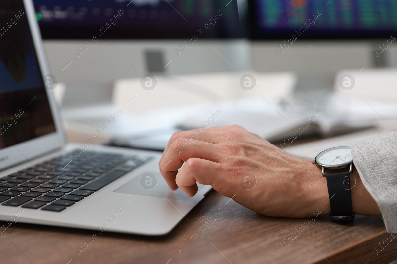 Photo of Financial trading specialist working on laptop at table in office, closeup