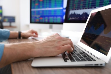 Photo of Financial trading specialist working on laptop at table in office, closeup