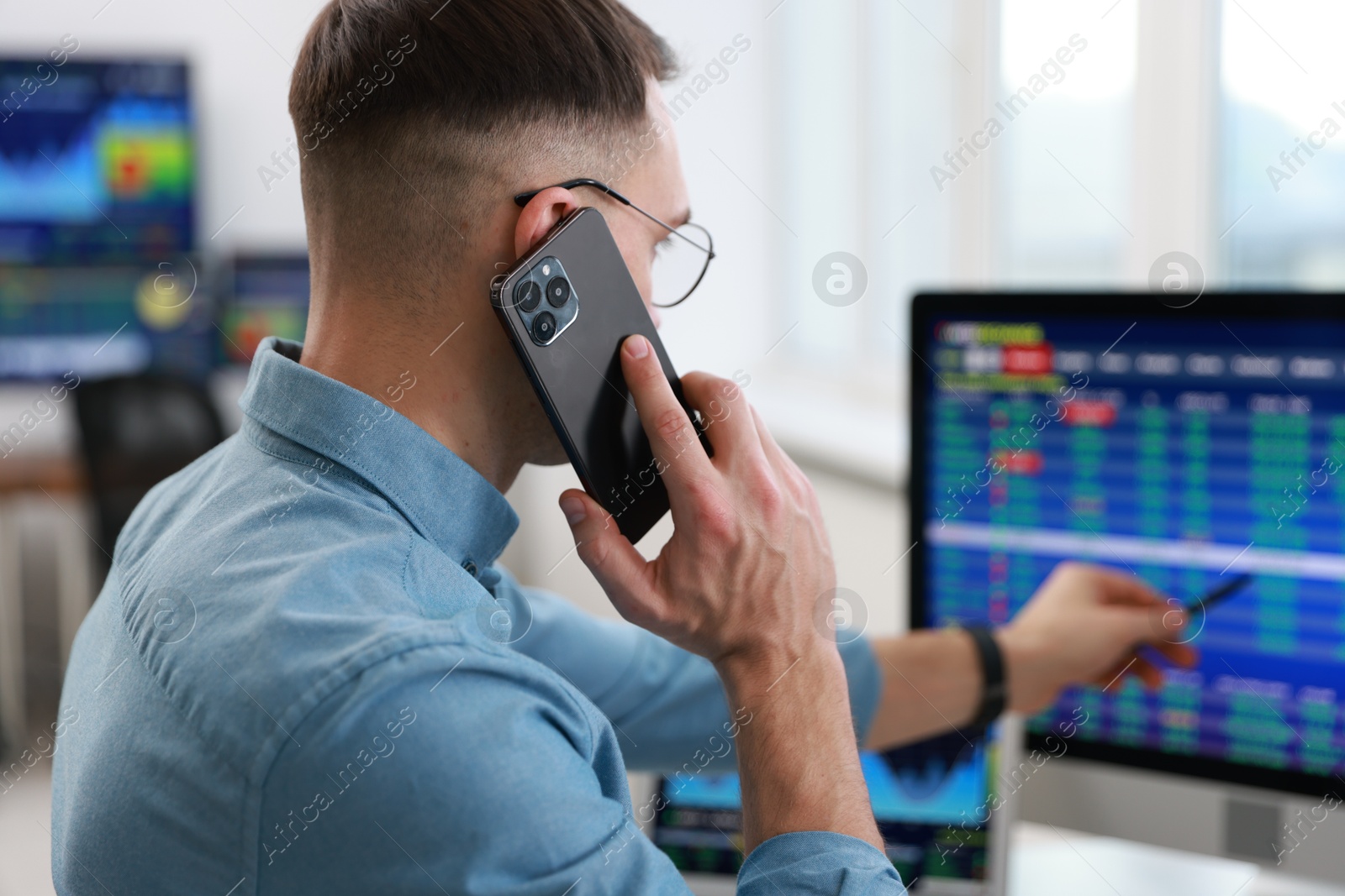 Photo of Financial trading specialist talking on phone in office