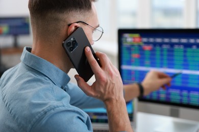 Photo of Financial trading specialist talking on phone in office