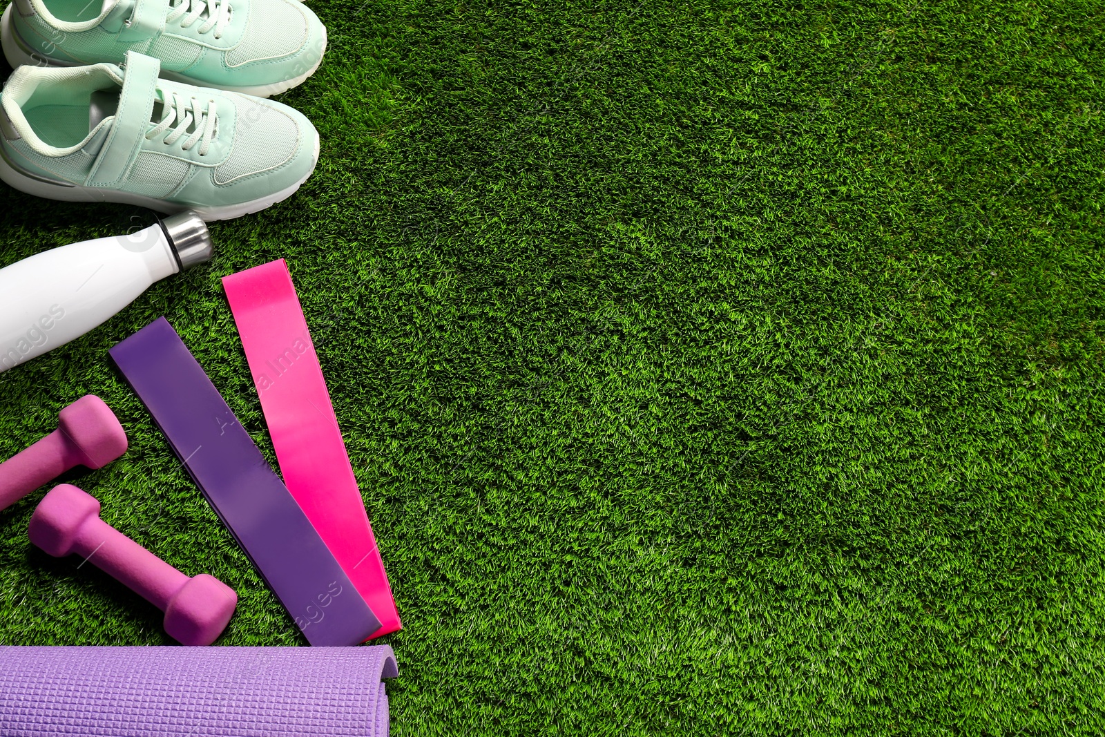 Photo of Different sports equipment on artificial grass, flat lay. Space for text