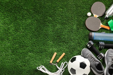 Photo of Different sports equipment on artificial grass, flat lay. Space for text