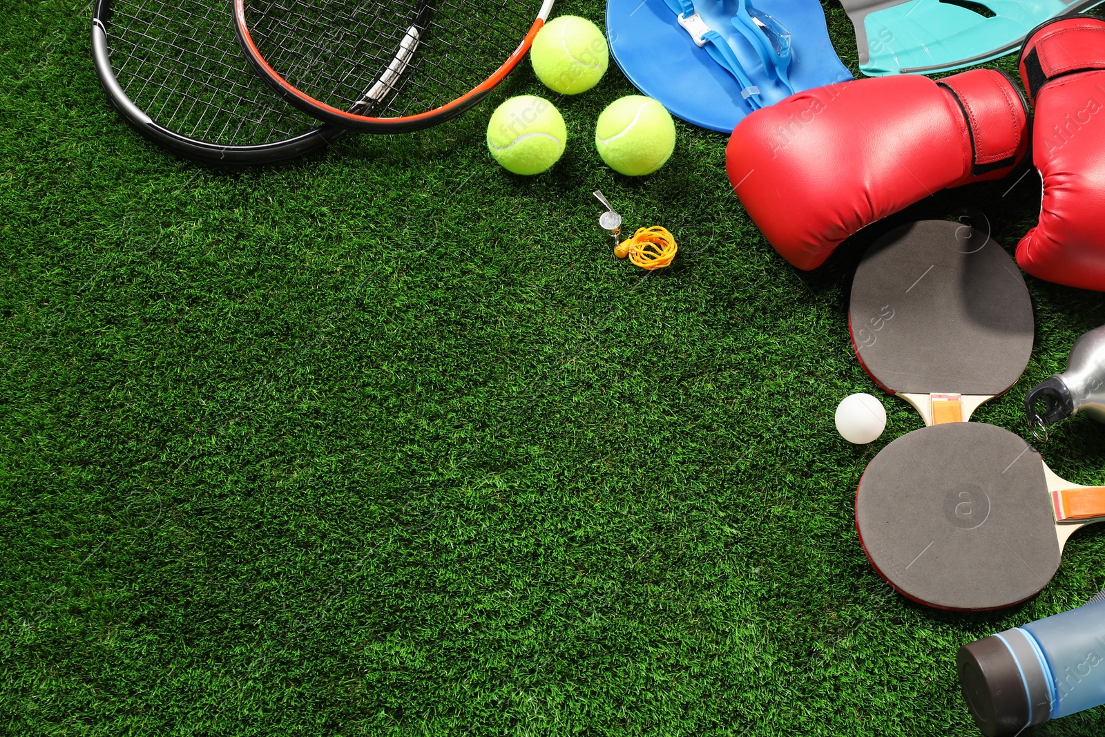 Photo of Different sports equipment on artificial grass, flat lay. Space for text