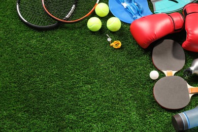 Photo of Different sports equipment on artificial grass, flat lay. Space for text