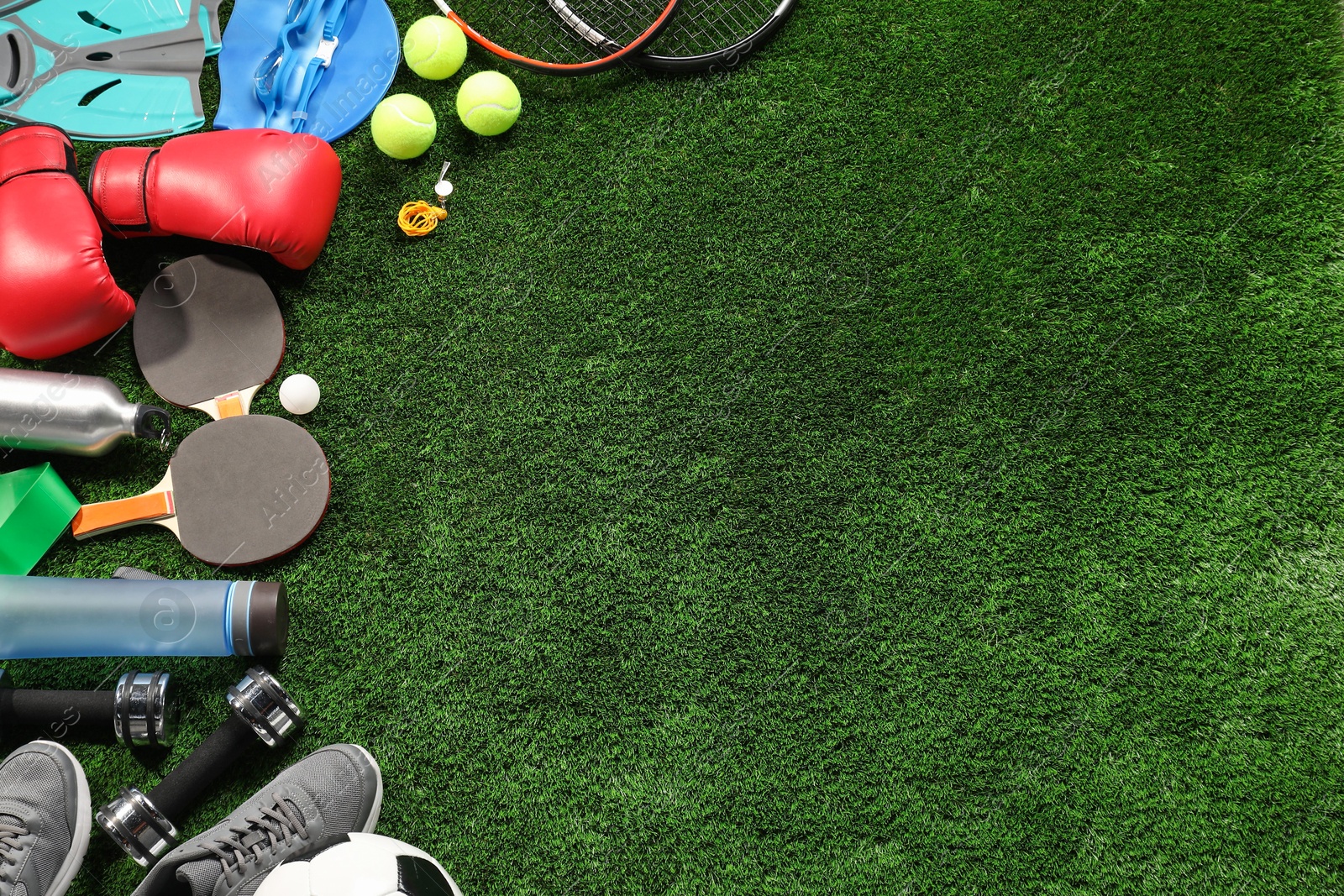 Photo of Different sports equipment on artificial grass, flat lay. Space for text