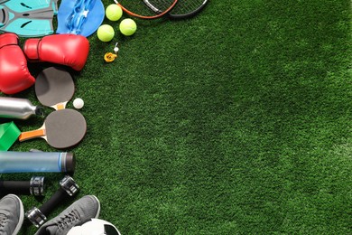 Photo of Different sports equipment on artificial grass, flat lay. Space for text