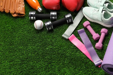 Photo of Different sports equipment on artificial grass, flat lay. Space for text