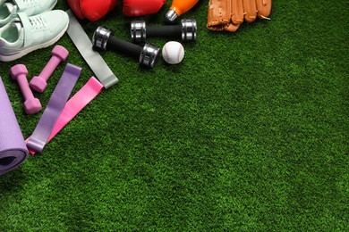 Photo of Different sports equipment on artificial grass, flat lay. Space for text