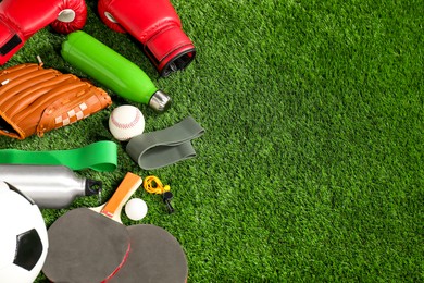 Photo of Different sports equipment on artificial grass, above view. Space for text