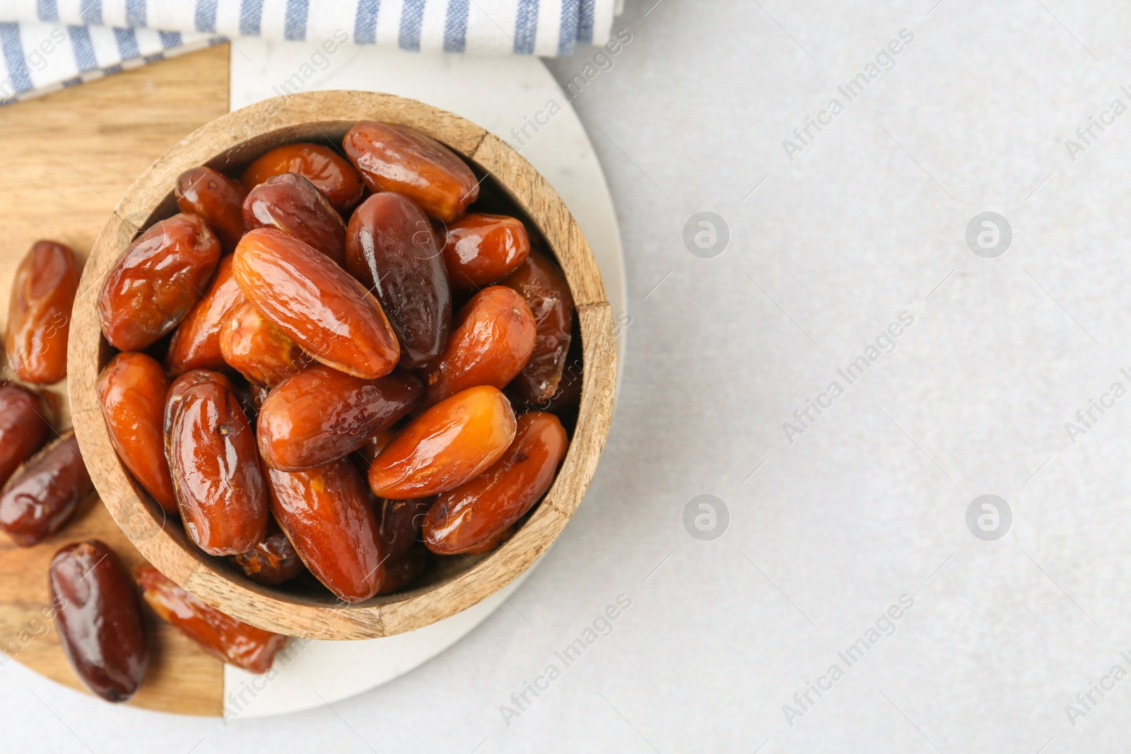 Photo of Tasty dried dates in bowl on white table, top view. Space for text