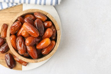 Photo of Tasty dried dates in bowl on white table, top view. Space for text