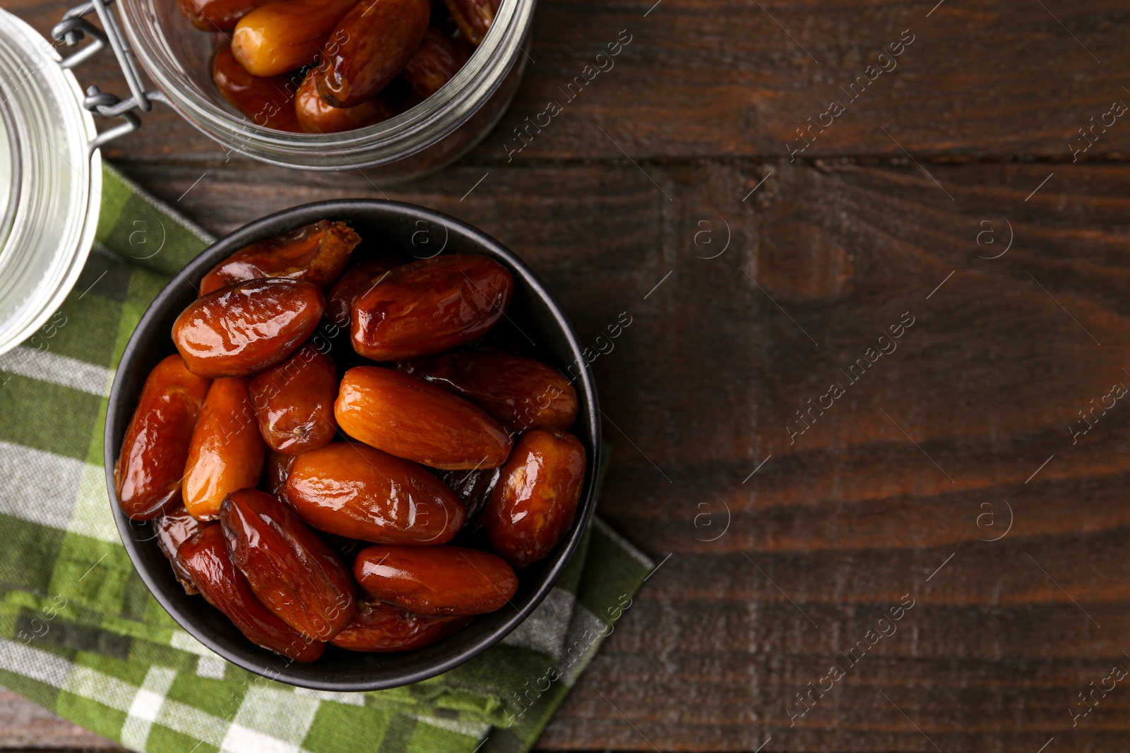 Photo of Tasty dried dates in bowl and jar on wooden table, flat lay. Space for text