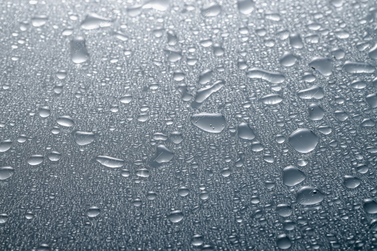 Photo of Water drops on grey glass surface, closeup